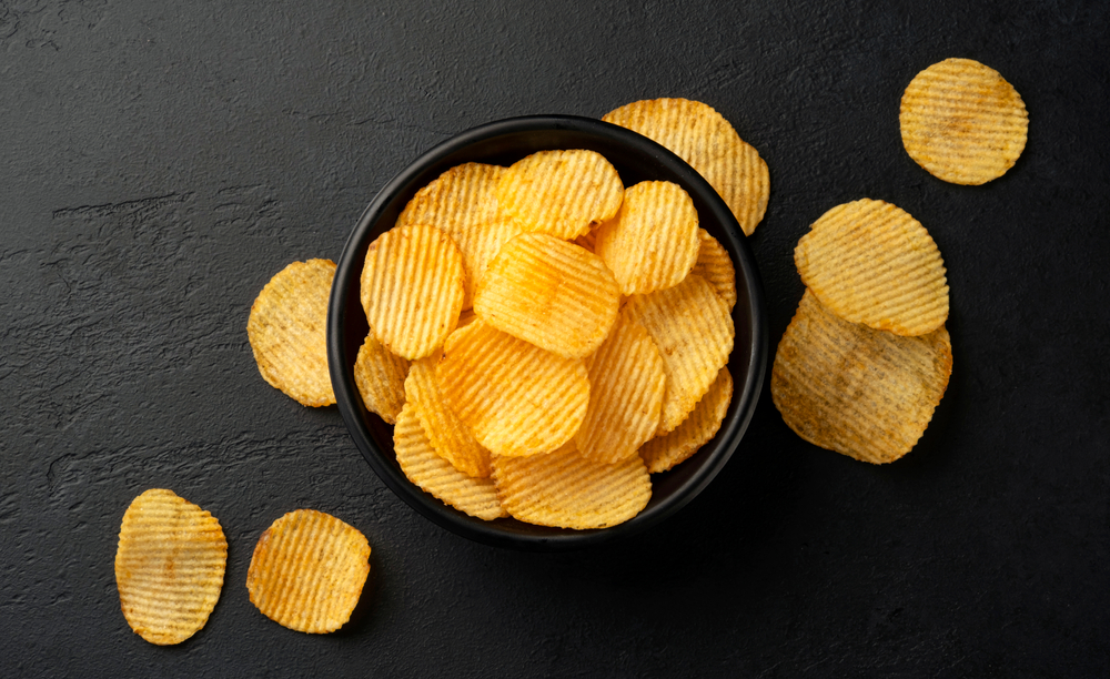 Ridged,Potato,Chips,In,Bowl,On,Black,Background,With,Copy